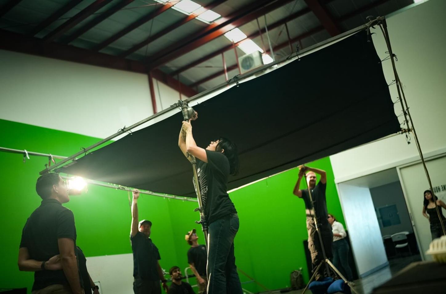 Crew rigging lights on a green screen stage